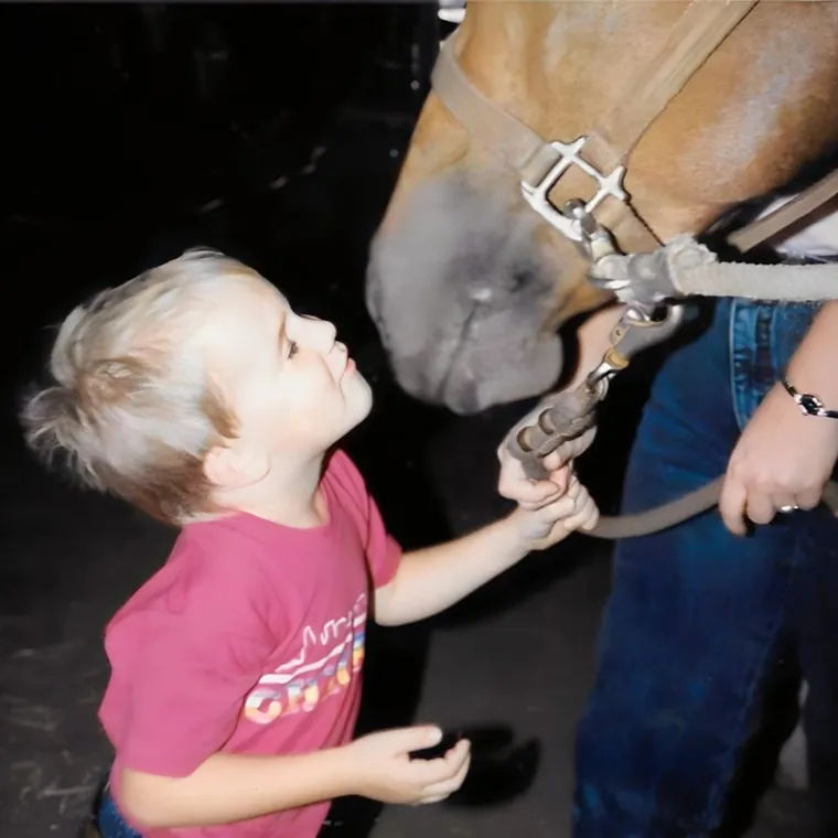William Horschak as a young boy looking up at a horse and holding its lead