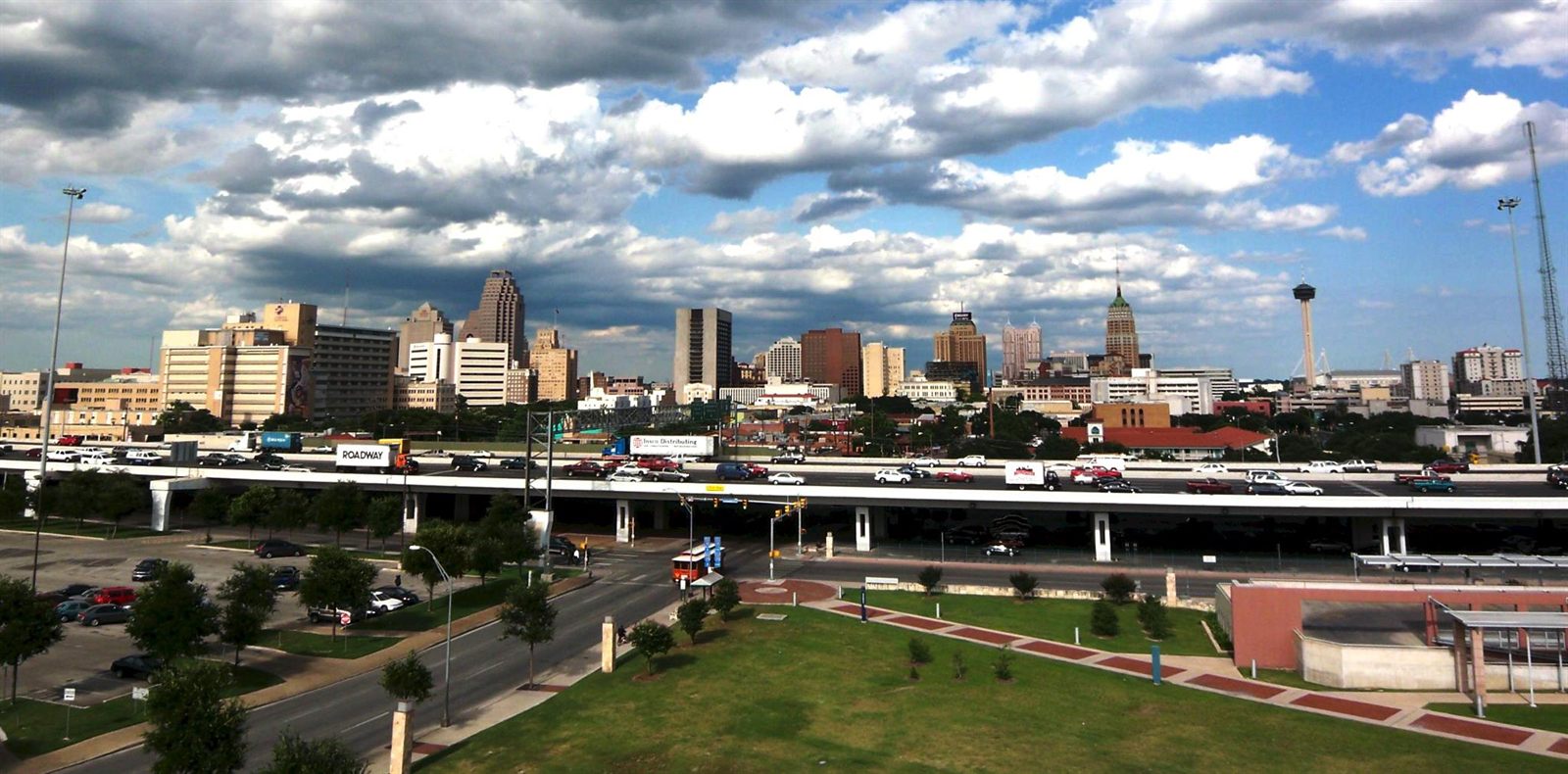The downtown San Antonio skyline under a cloudy Texas sky, with the Tower of the Americas at right